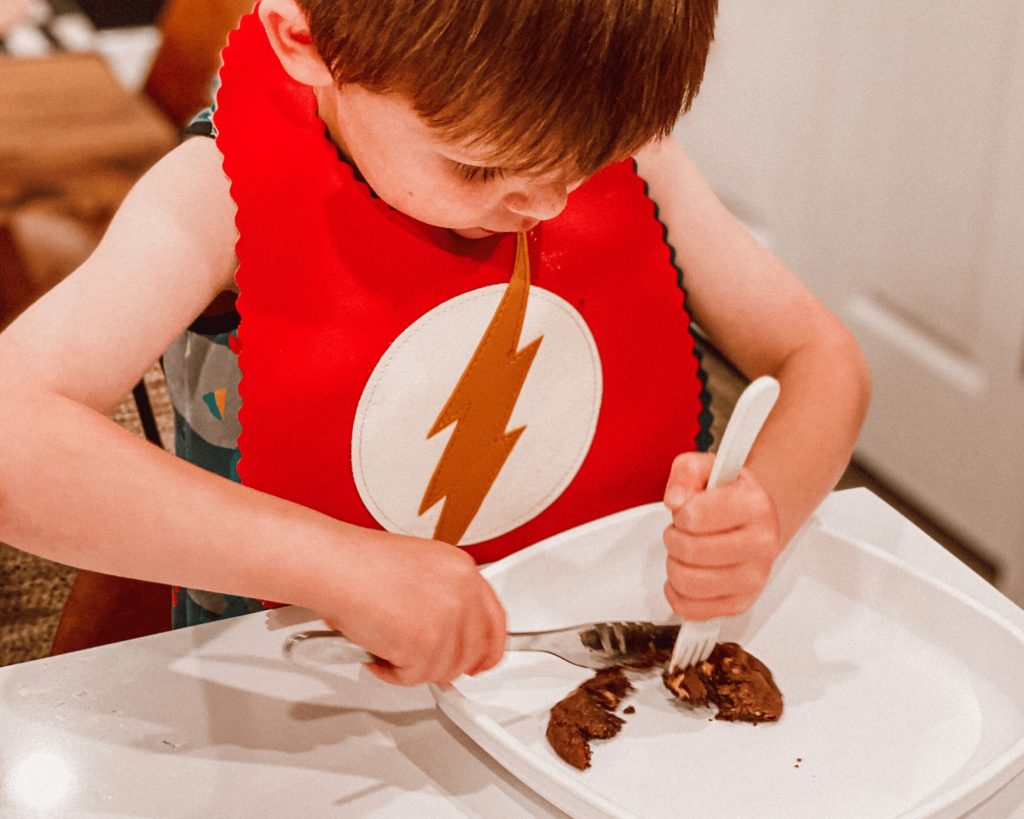 boy eating cookie with fork and knife 